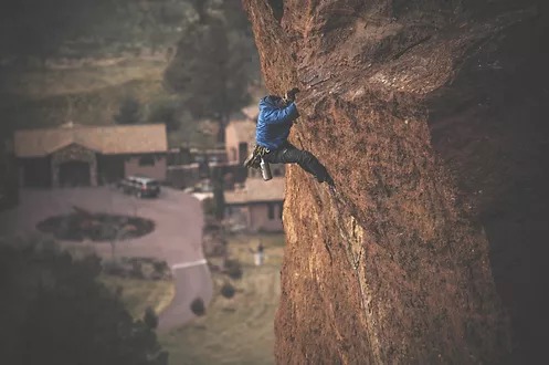 A man climbing up the side of a rock wall.