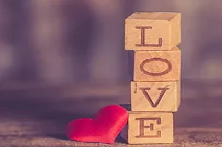 A red heart sitting next to the word love on blocks.